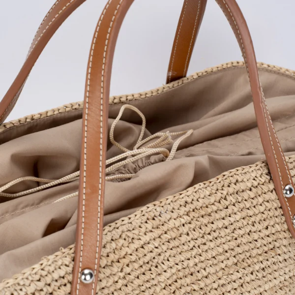 sac en raphia beige et lanières de cuir marron en gros plan