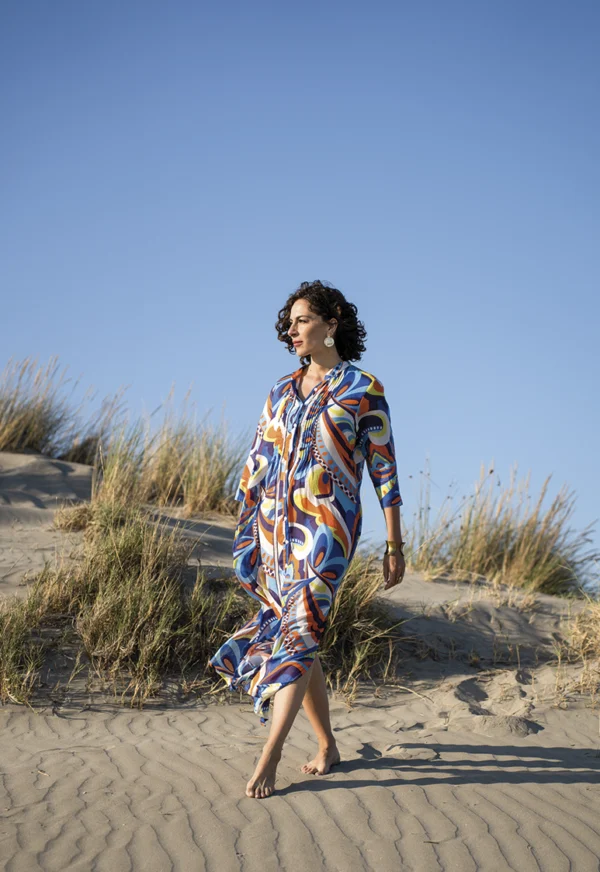 Photo posées une femme qui marche sur le sable en robe colorées